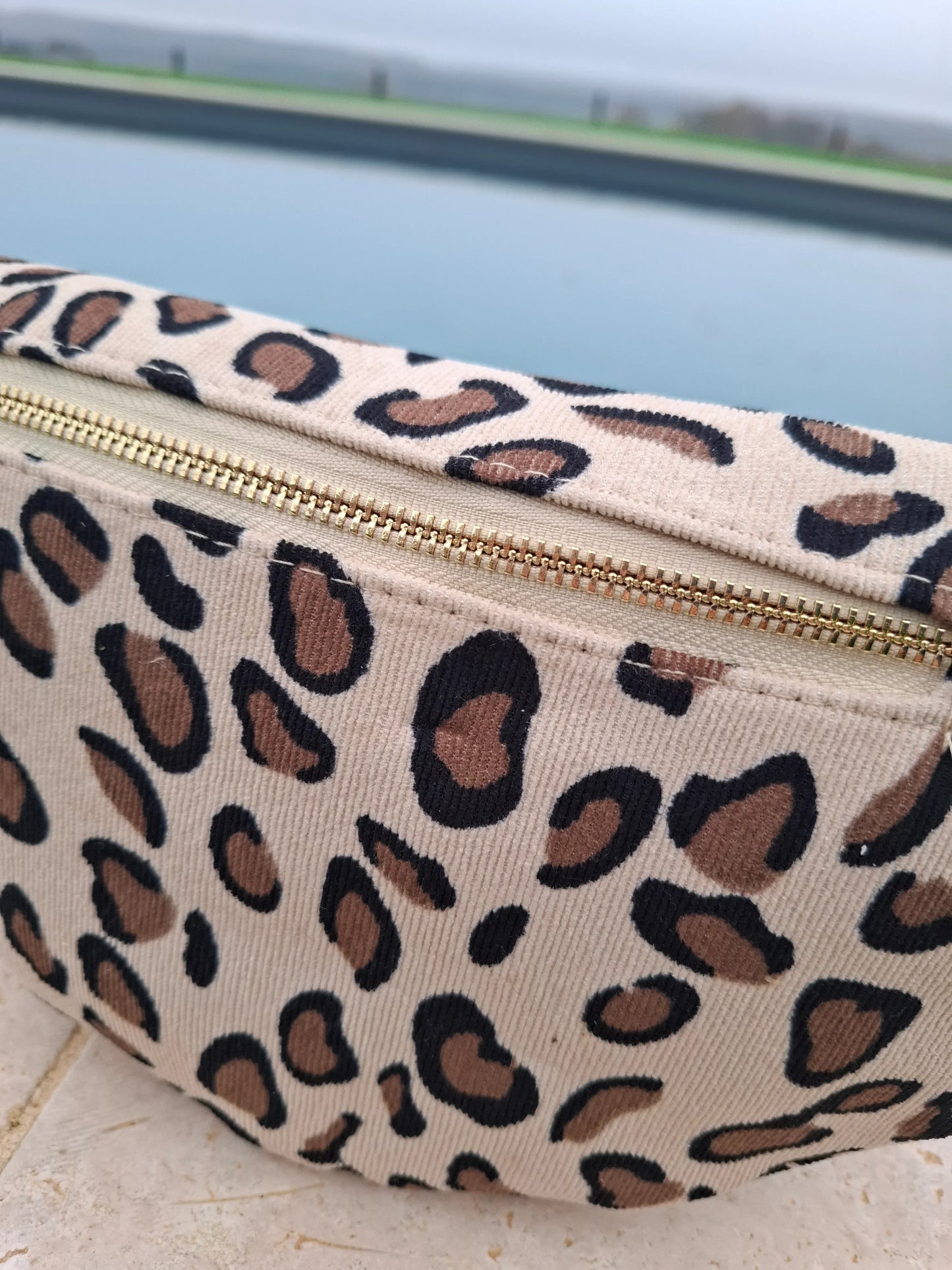 Riñonera de pana color beige con estampado de leopardo marrón y negro de motivos grandes