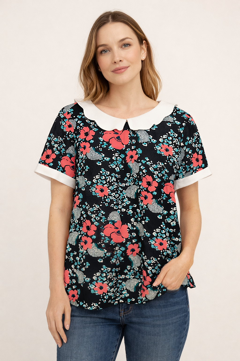 Blouse fleurie bleu marine à col Claudine blanc et manches courtes, motif floral rouge et turquoise.