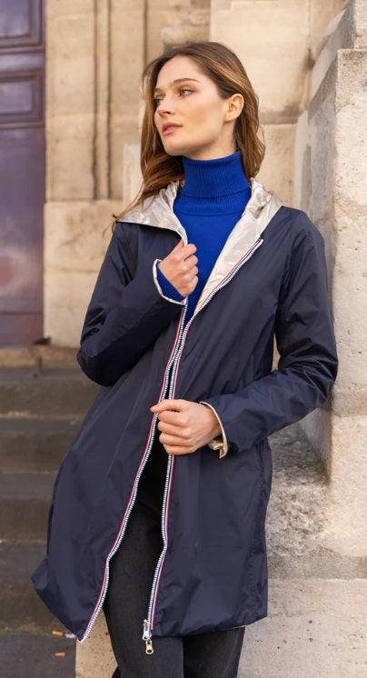 Woman wearing a navy Laura Jo raincoat and blue turtleneck, outdoor stone background, Le Petit Placard