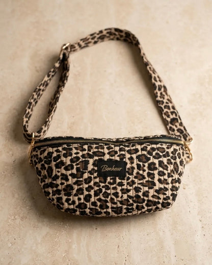 Sac banane matelassée léopard avec bandoulière réglable et zip, petite pochette chic. Bonheur affiché sur un badge.