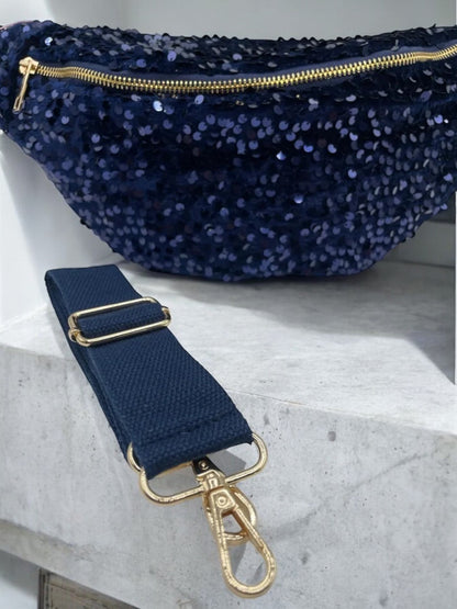 Sac banane bleu marine à paillettes avec bandoulière réglable et attache dorée, posé sur une marche.