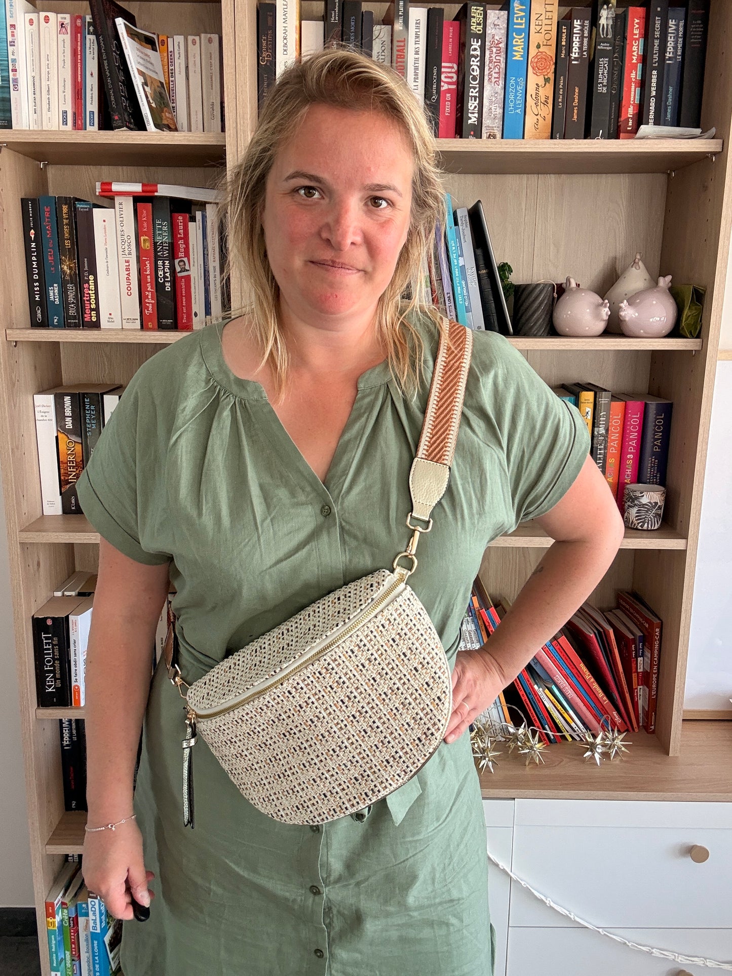 Sac banane tissu motif bohème – Noir, beige & camel porté en bandoulière par une femme devant une bibliothèque.