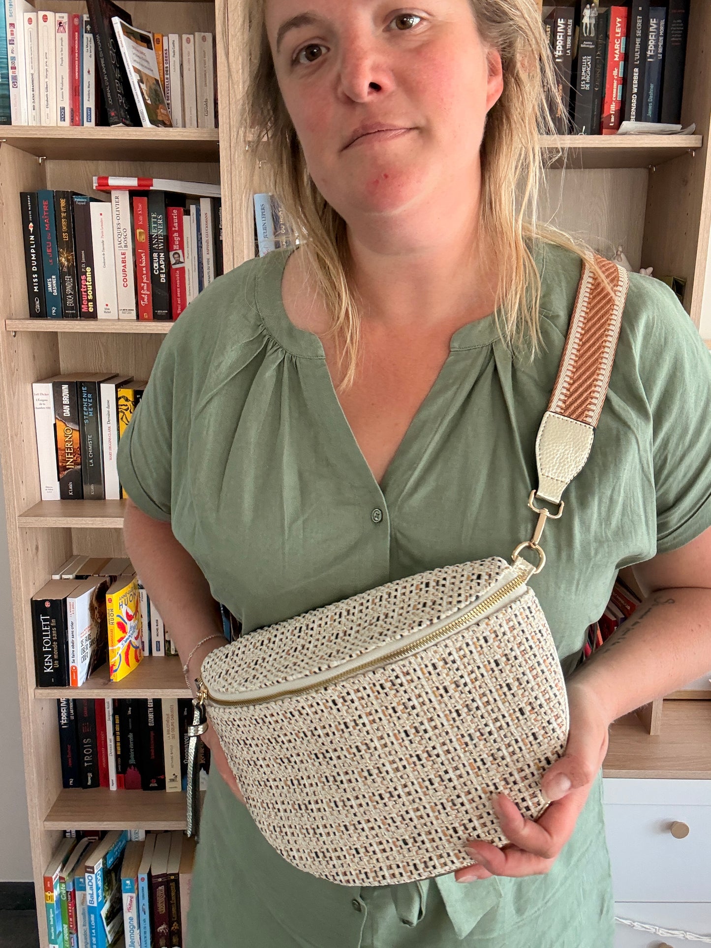Sac banane en tissu motif bohème noir, beige et camel portée en bandoulière par une femme dans une bibliothèque.