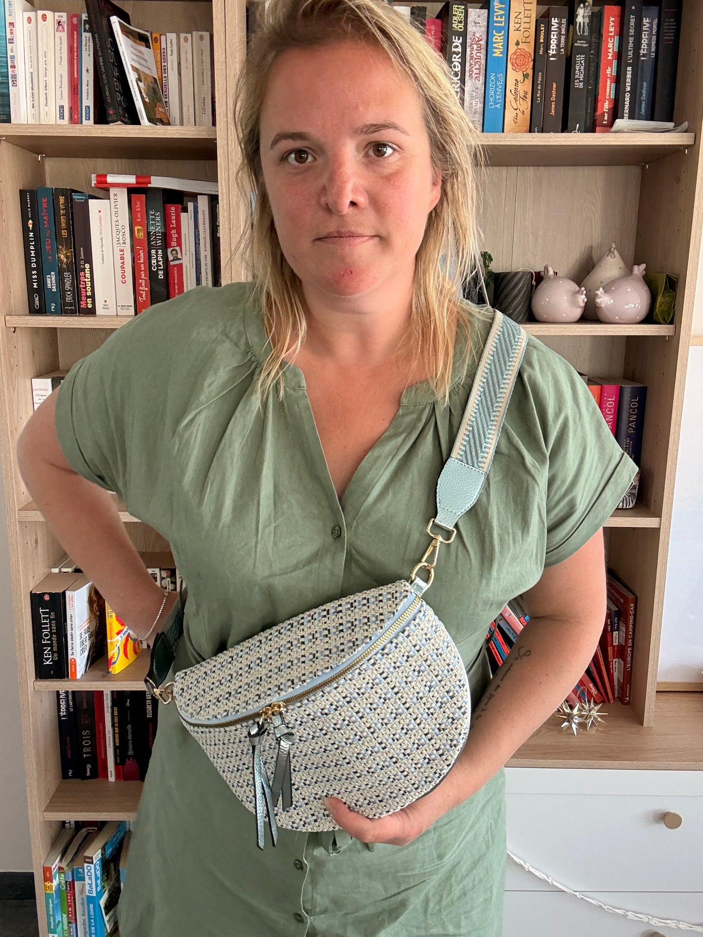 Sac banane en tissu à motif texturé bleu clair et beiges porté en bandoulière, posé sur la taille avec fermeture zippée et charmantes pampilles.