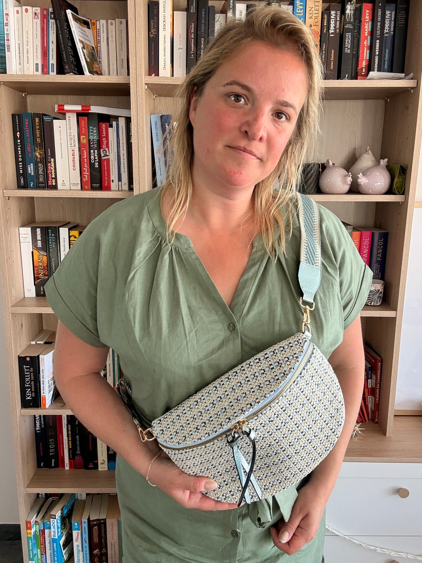 Sac banane en tissu à motif texturé noir, bleu et beige porté en diagonal, avec sangle fantaisie et fermeture zippée.