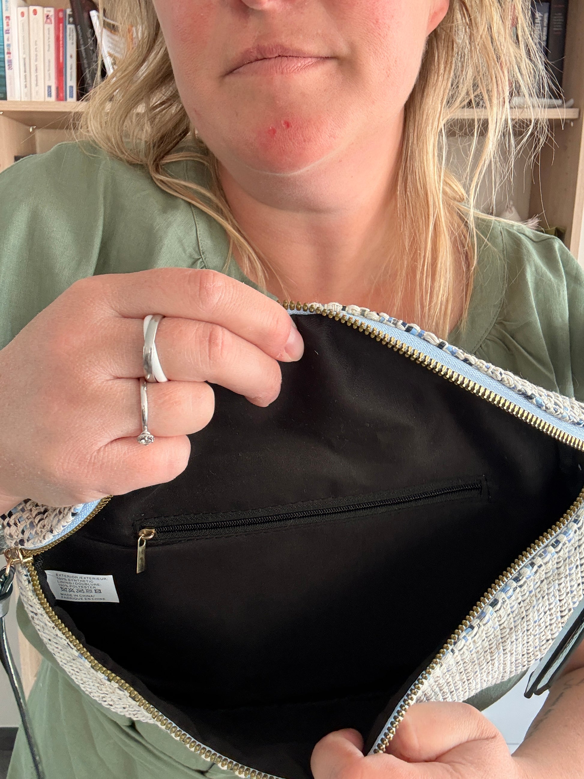 Sac banane en tissu ouvert pour montrer l’intérieur, avec poche zippée noire et doublure noire. Motif texturé sur l’extérieur et chaîne / sangle fantaisie visible.