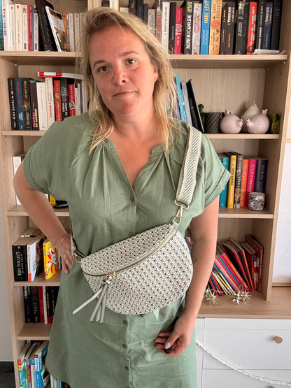 Sac Banane Tissu Texturé – Motif Blanc, Noir & Bleuté porté en bandoulière par une femme devant une bibliothèque.