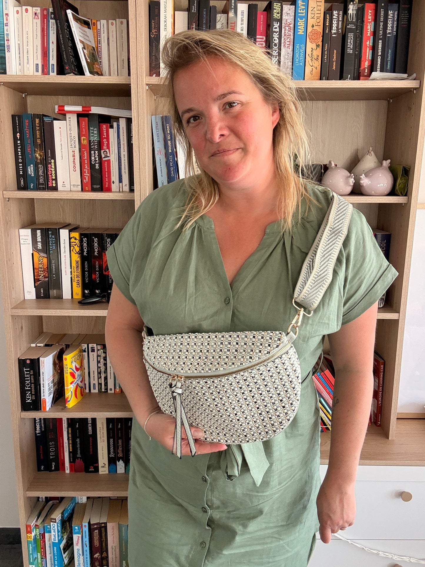 Sac Banane Tissu Texturé – Motif Blanc, Noir & Bleuté porté en bandoulière par une femme devant une bibliothèque.