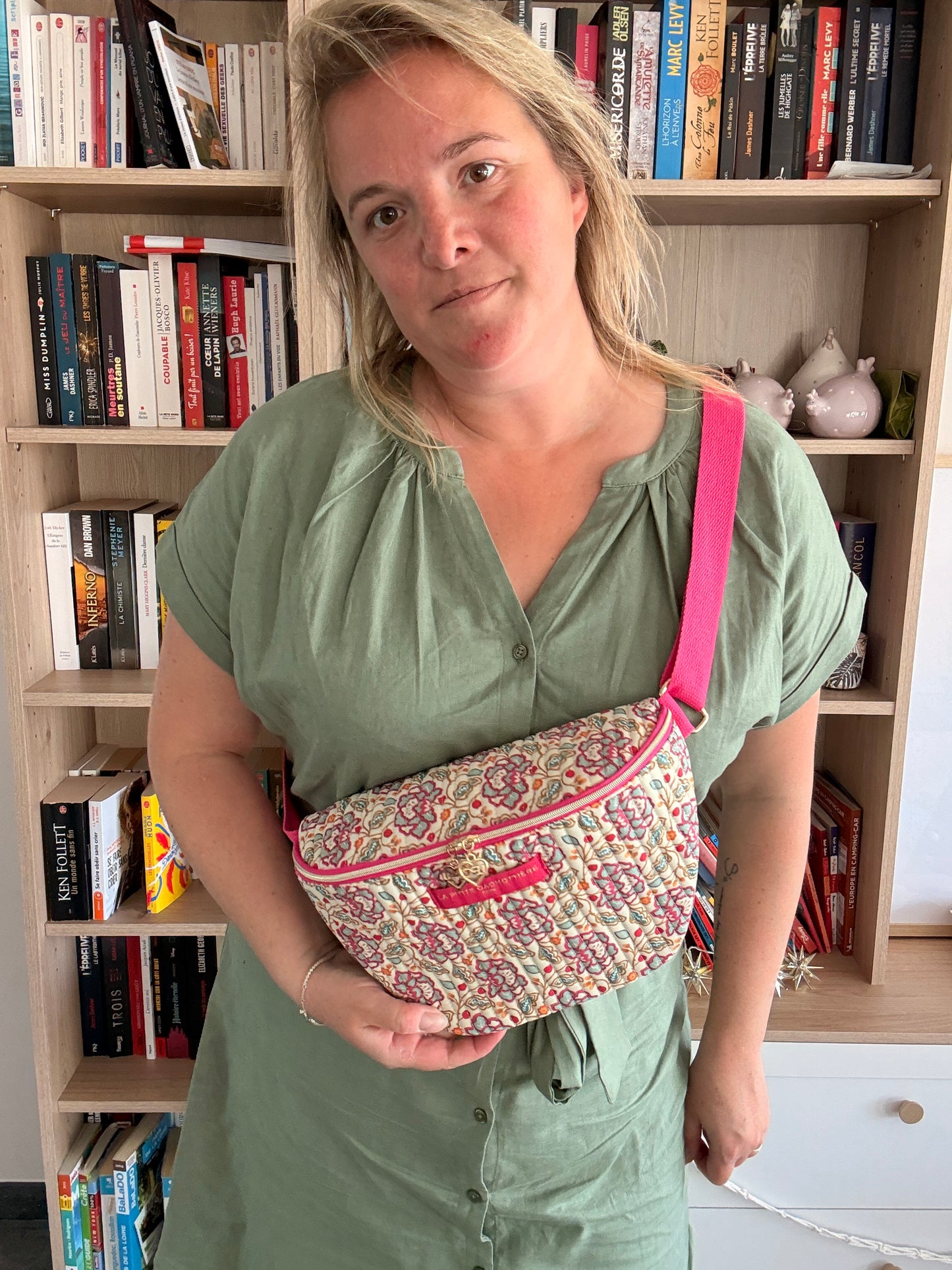 Homme/femme porte-sac banane Liberty fleuri rose sur harnais rose, ceinture beige et finitions dorées, posé sur le ventre.