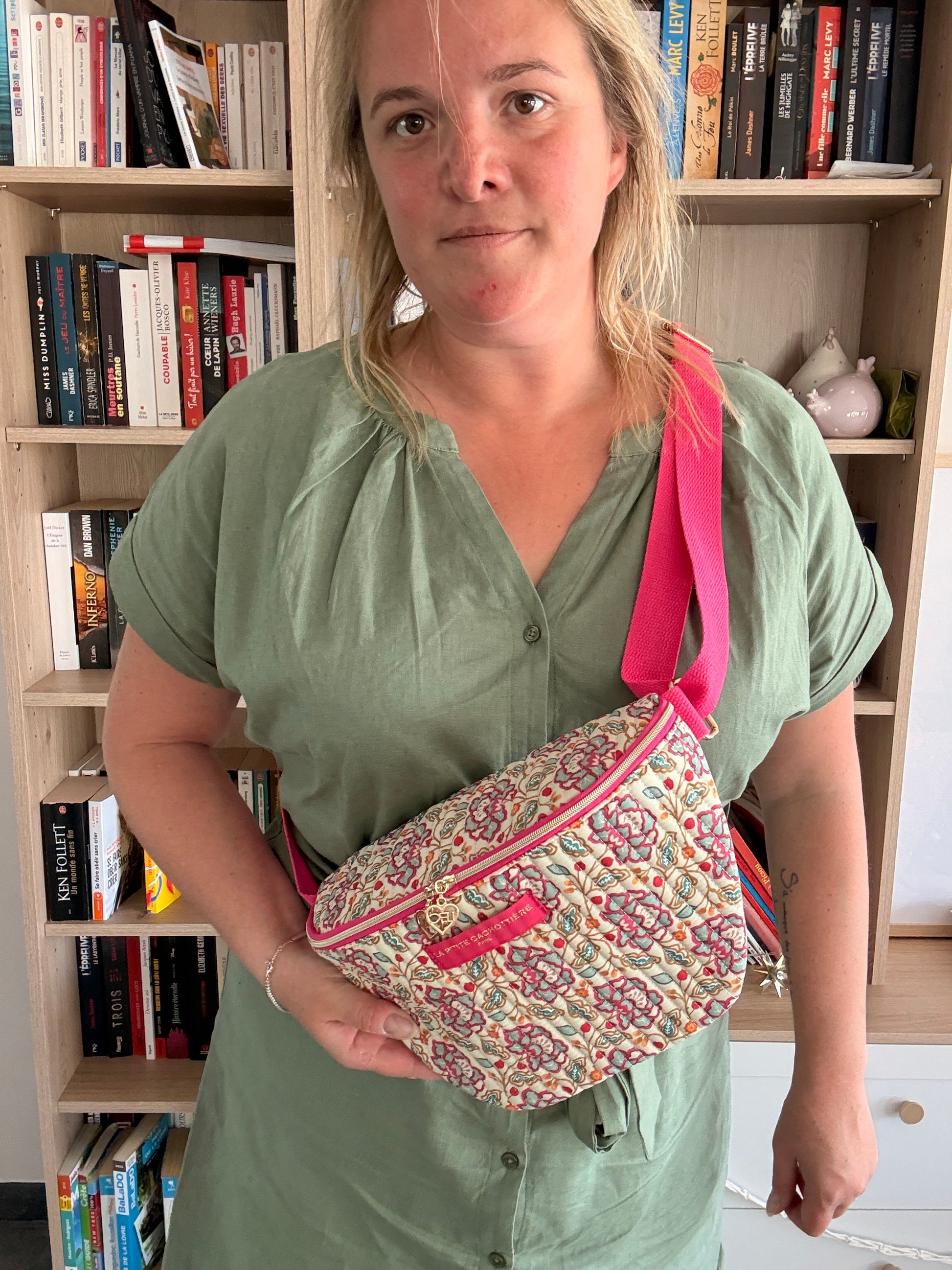 Sac banane Liberty fleuri rose porté en bandoulière, avec coton beige et finitions dorées visibles sur le zip et le détail.