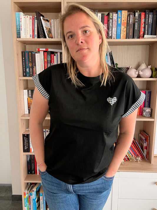 T-shirt femme noir coupe oversize avec détails vichy noir et blanc, porté par une femme devant une bibliothèque.