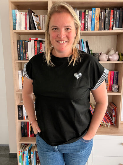 T-shirt femme noir oversize avec détails vichy noir et blanc, porté par une femme devant une étagère de livres.