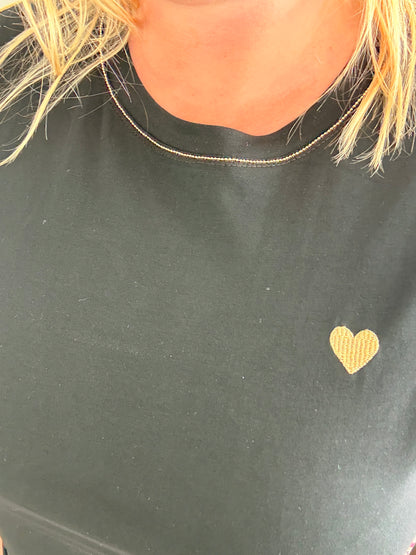 T-shirt noir avec petit cœur doré sur la poitrine et col rond.