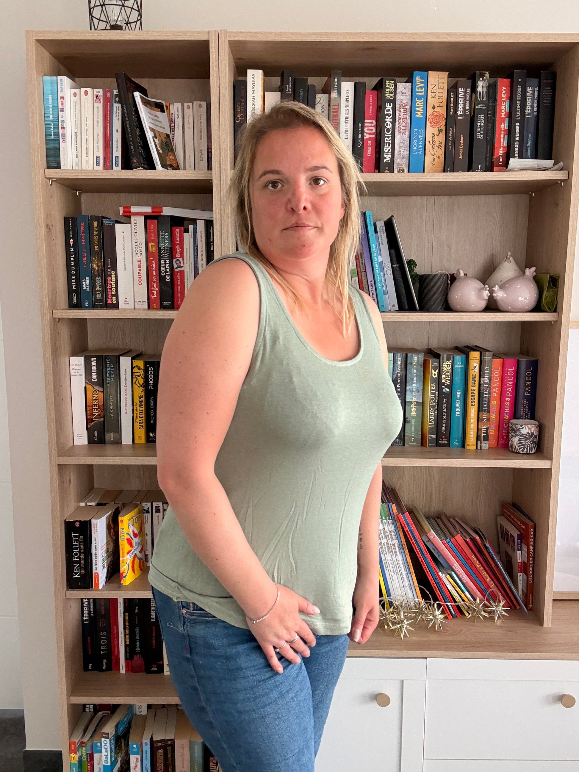 Débardeur coton-lin kaki porté par une femme debout, physique moyenne, bibliothèque en arrière-plan, look estival décontracté.