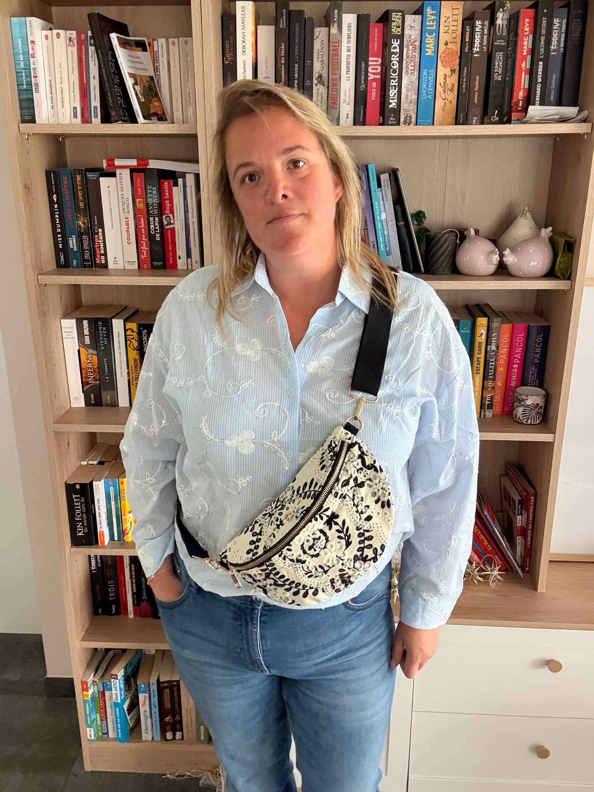 Sac Banane Femme Floral Noir et Blanc porté en travers, légère et pratique, sur fond de bibliothèque.
