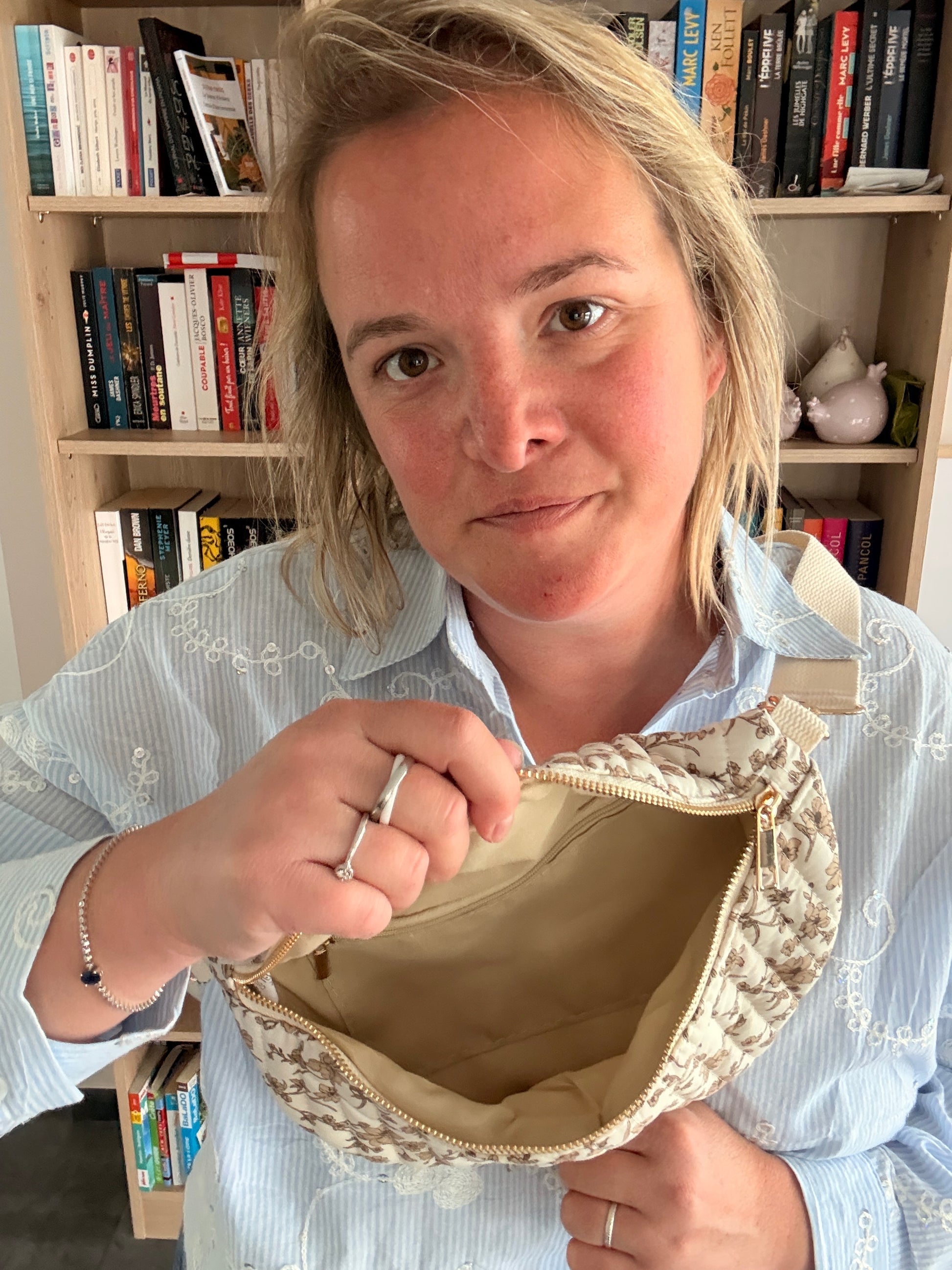 Sac banane femme fleuri taupe fond ivoire avec zip doré et bandoulière réglable, ouverture montrant compartiment intérieur beige.