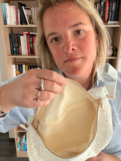 Sac banane femme en broderie anglaise crème ouverte pour montrer l’intérieur spacieux et la poche zippée centrale.