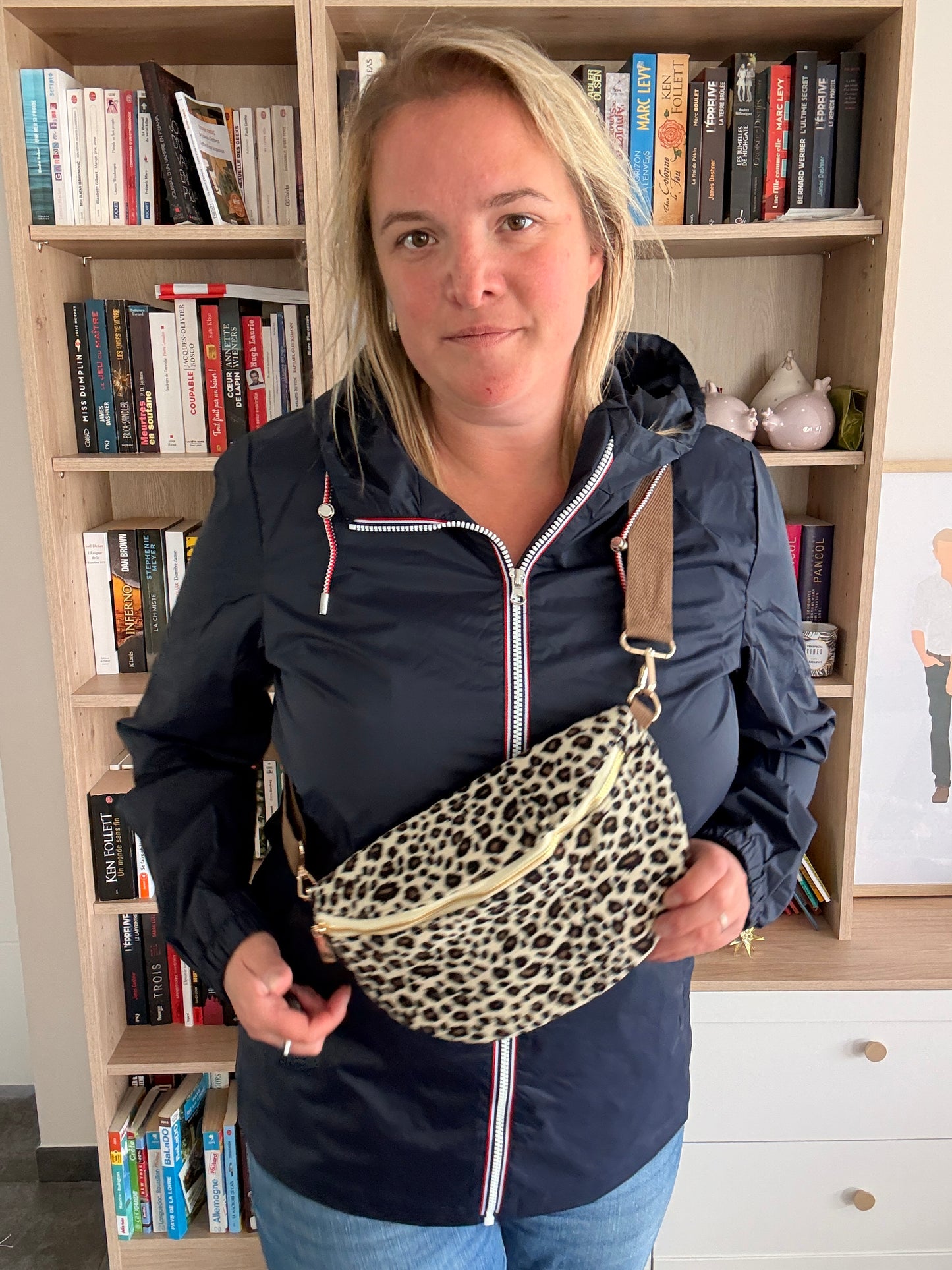 Sac banane velours côtelé imprimé léopard beige, noir et doré portée en bandoulière par une femme.