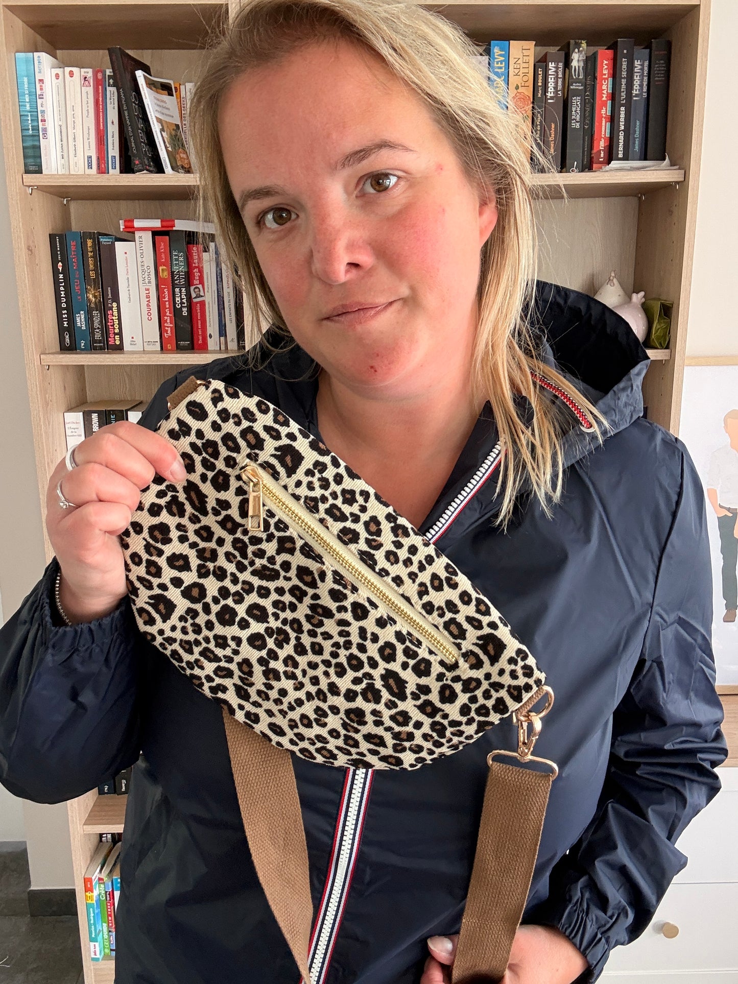 Sac Banane Velours Côtelé Imprimé Léopard – beige à noir et doré, porté sous forme de pochette en leopard sur l’avant, zippée dorée, avec bandoulière amovible beige et lanière marron, en salon.