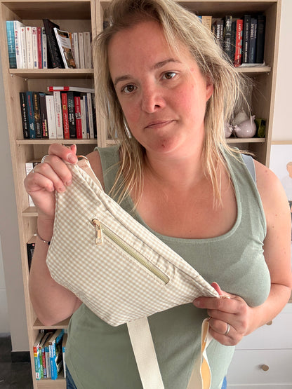 Sac banane en coton motif vichy beige et blanc avec cœur rouge - femme tenant la banane souriante, zippée devant.