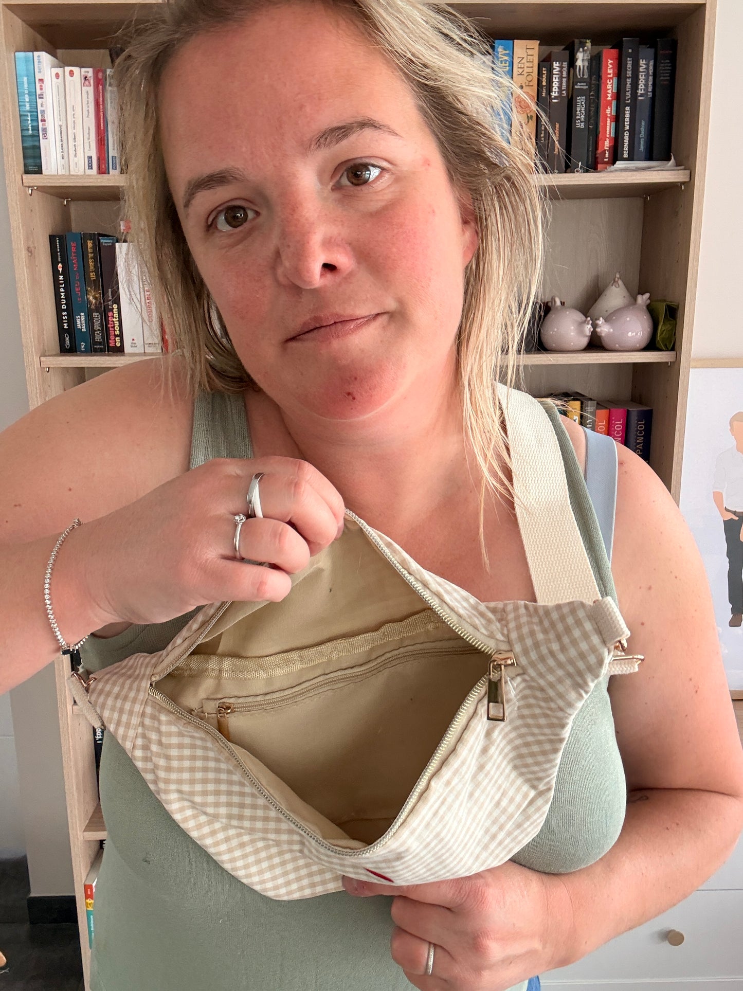 Sac banane en coton motif vichy beige et blanc avec cœur rouge : femme tenant facilement le sac ouvert pour montrer l’intérieur spacieux.