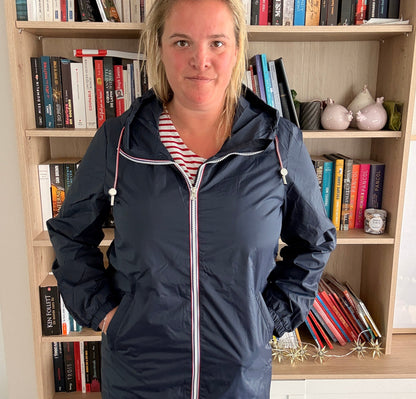 Parka manteau bleu marine imperméable Laura Jo, longueur longue, doublure fine, femme posant en intérieur devant une étagère de livres.