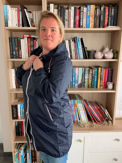 Laura Jo - Parka manteau bleu marine imperméable long avec doublure légère portée par une femme devant une bibliothèque.