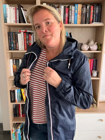 Parka manteau bleu marine imperméable long, femme portant une doublure légère et zippée, en intérieur.