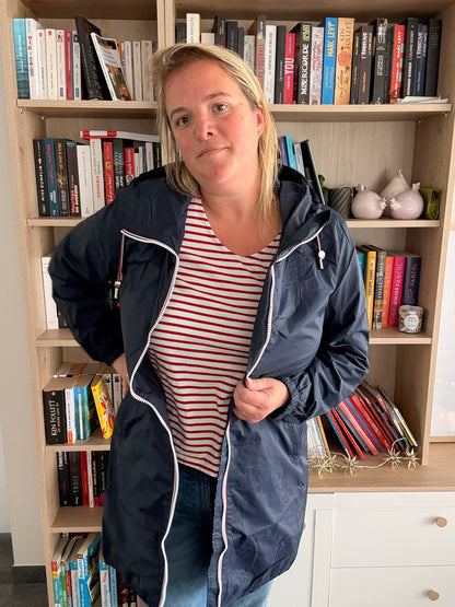 Parka manteau bleu marine imperméable longue, femme debout avec zips visibles, intérieur doublure légère, devant bibliothèque. Laura Jo.