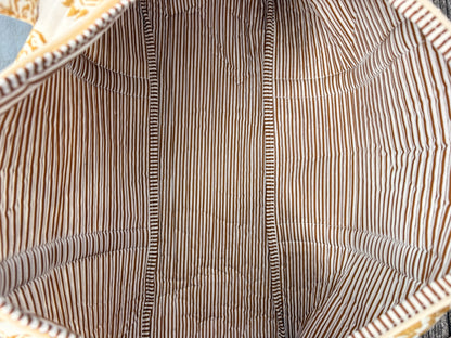 Sac polochon matelassé imprimé baroque doré vu de l’intérieur, doublure à rayures brunes et blanches.