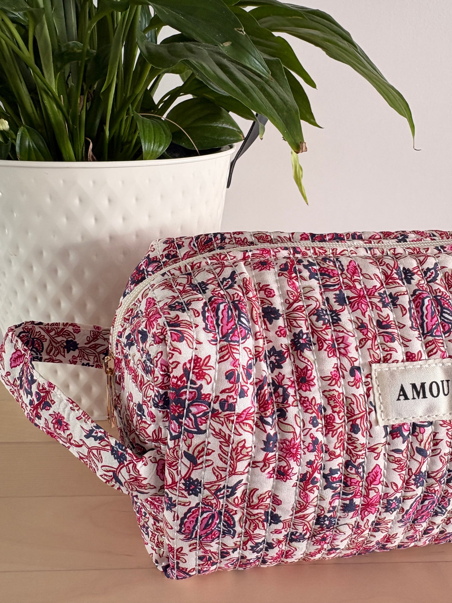 Grande trousse maquillage femme imprimé floral rose, pochette zippée à grande capacité posée sur table, fleurie et fonctionnelle.