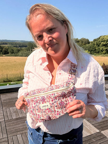 Sac banane Liberty rose imprimé fleuri pour femme en extérieur, porte-bagagesné sous un ciel clair.