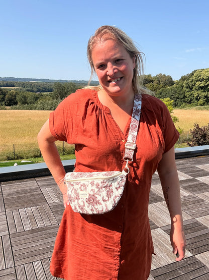 Sac banane Toile de Jouy Bordeaux porté en bandoulière par une femme sur une terrasse en plein air. Amour et style féminin.