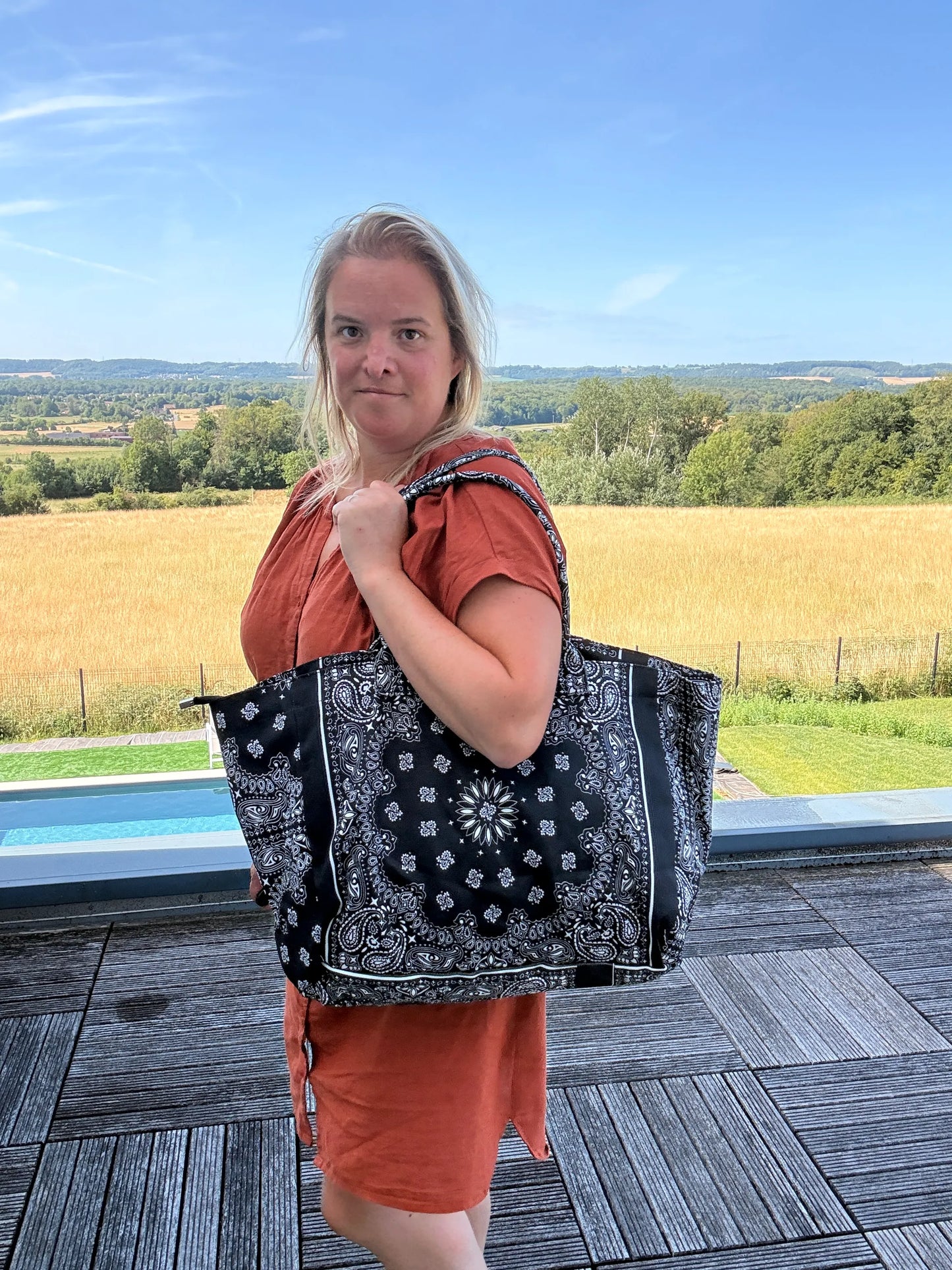 Sac Polochon Épaule Coton Paisley Noir – Grand Format Zippé porté sur l’épaule par une femme, paysage champêtre en arrière-plan.