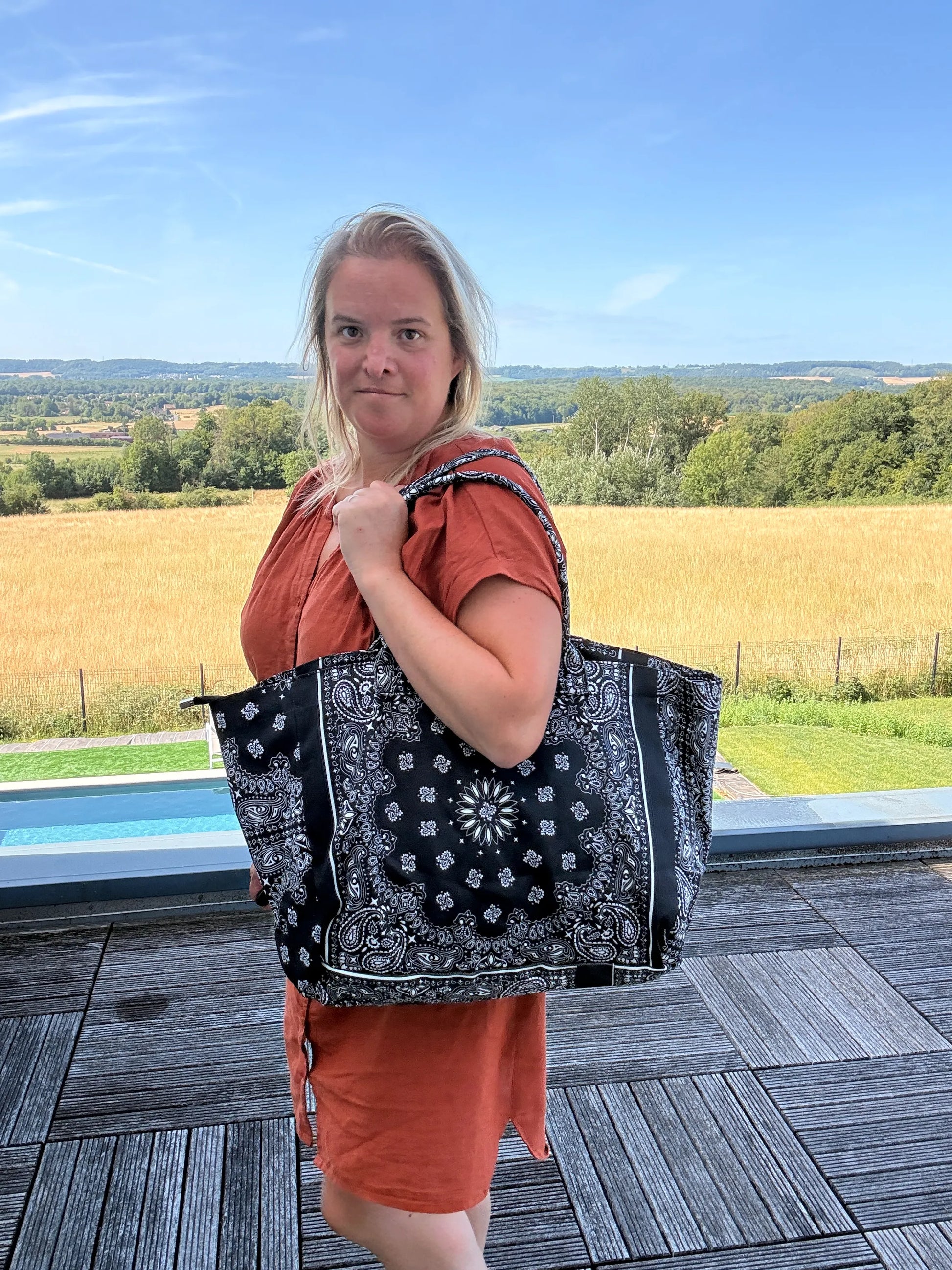 Sac Polochon Épaule Coton Paisley Noir – Grand Format Zippé porté sur l’épaule par une femme, paysage champêtre en arrière-plan.