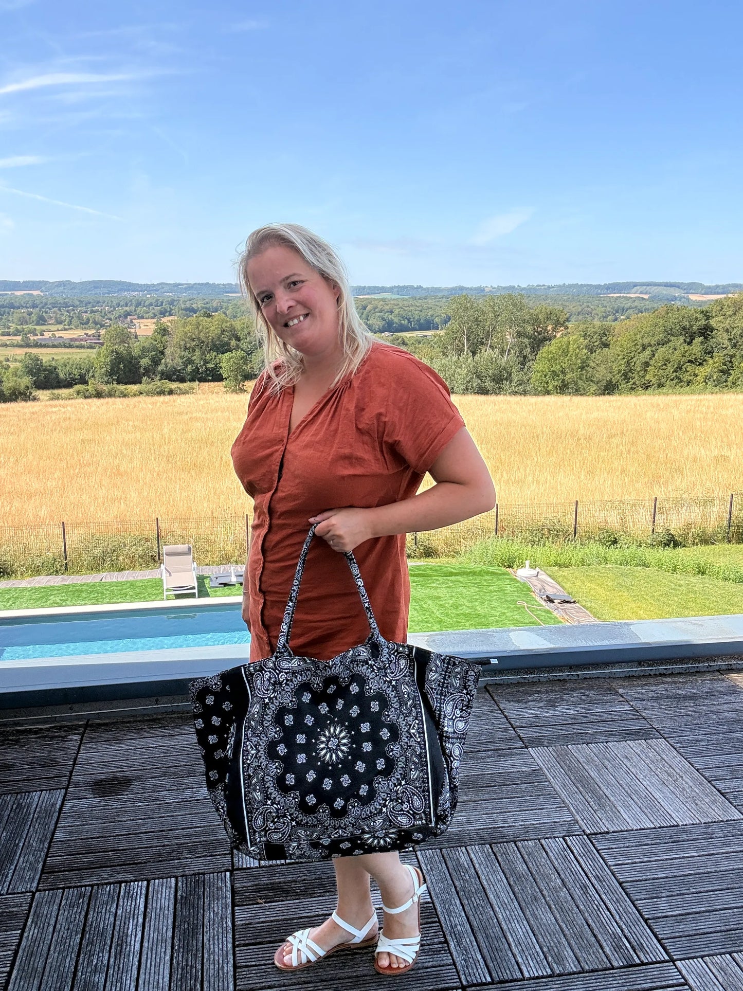 Sac polochon é shoulder en coton paisley noir grand format zippé, porté par une femme devant une vue champêtre.