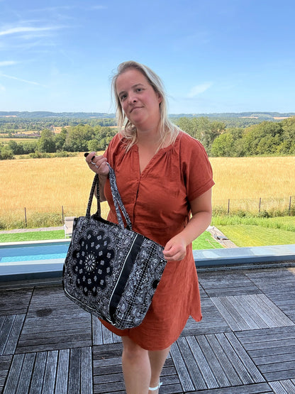 Sac polochon épaule coton Paisley noir grand format zippé, porté par une femme en robe orange dehors près d’une piscine.