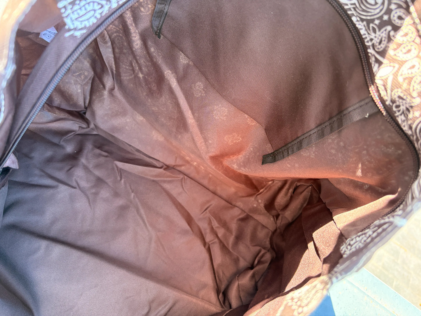 Grand sac polochon marron zippé, intérieur spacieux et sombre avec poche élastique et fermeture éclair visible sur le bord.