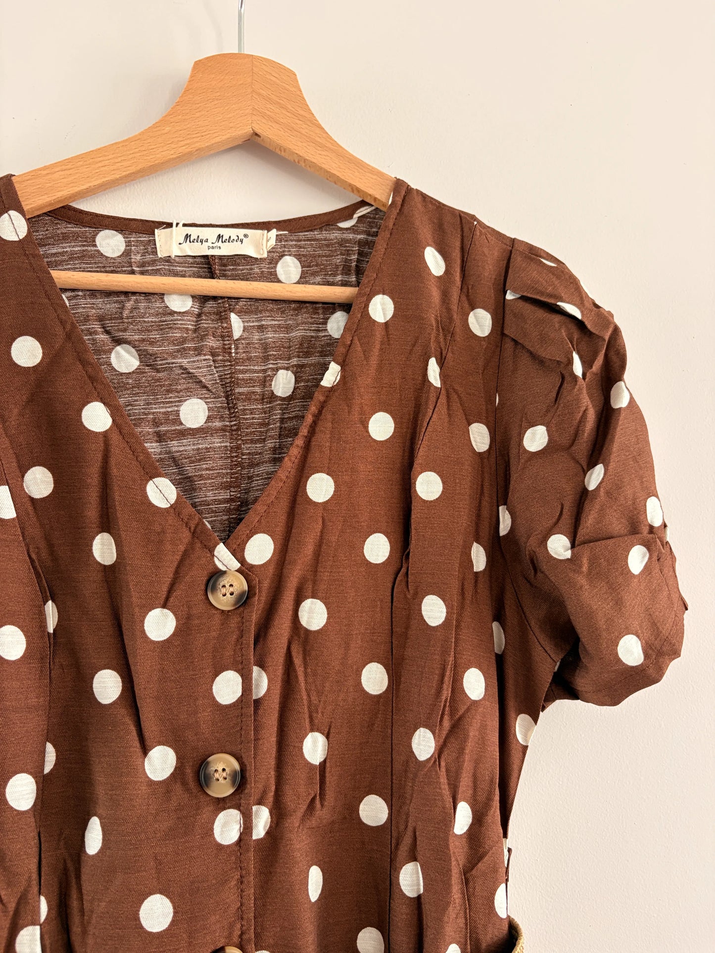 Robe midi à pois beige et marron, manches bouffantes, col en V et ceinture assortie, style vintage sur cintre.