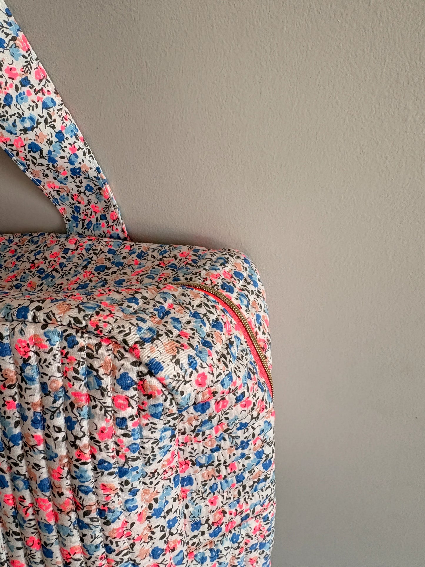 Sac polochon matelassé floral imprimé Liberty lilas, rose et bleu avec fermeture zippée et poignée.