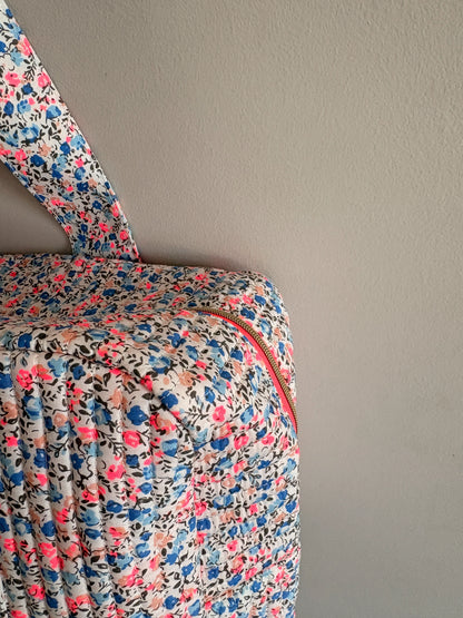 Sac polochon matelassé floral imprimé Liberty lilas, rose et bleu avec fermeture zippée et poignée.