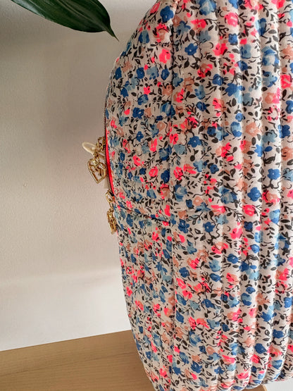 Sac polochon matelassé floral imprimé Liberty lilas, rose et bleu avec zipper doré et détails chaînes.