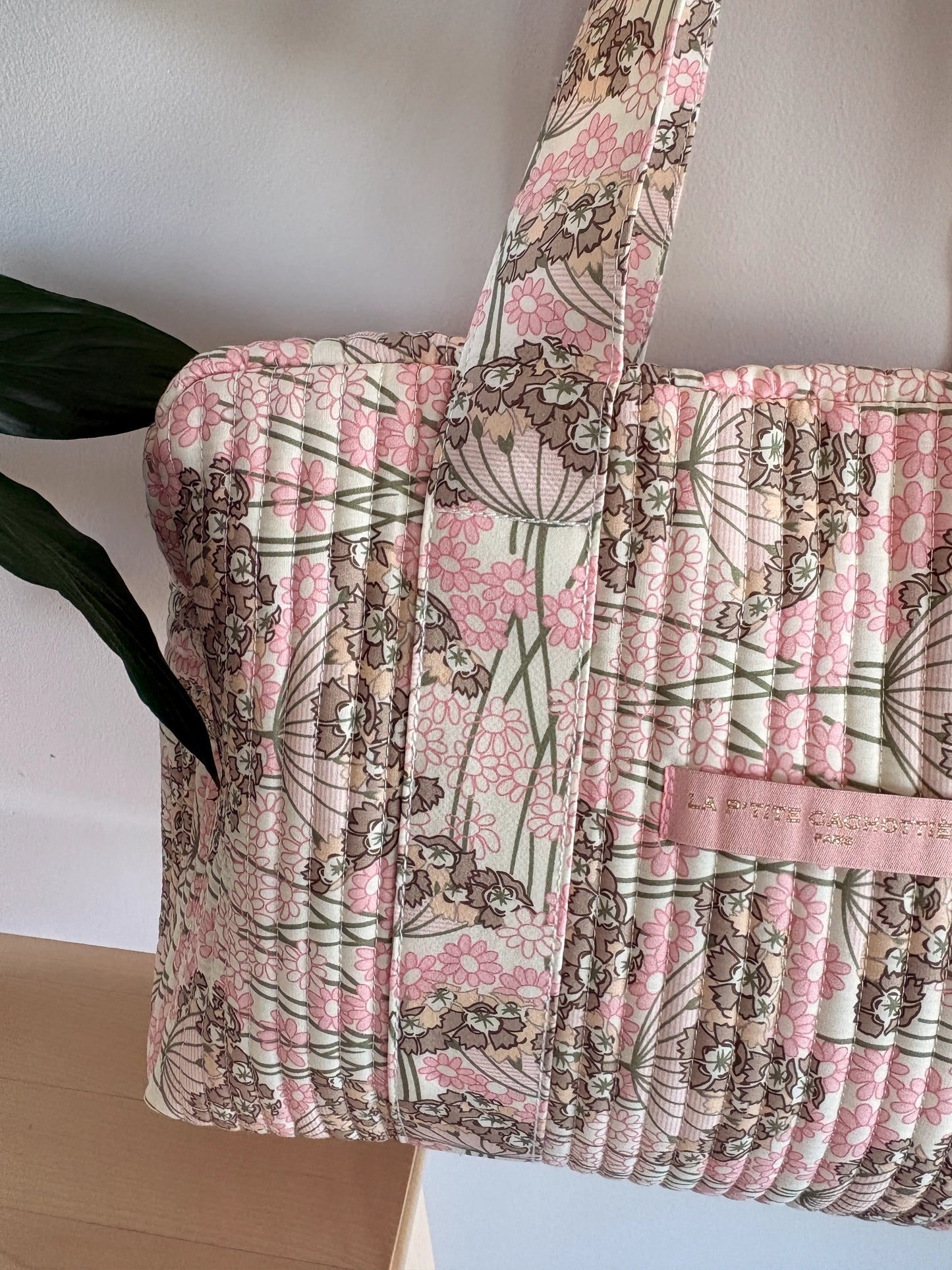 Sac polochon matelassé rose fleuri avec poignée; motif floral et cuirette rose clair, étiquette “SAC CAM?.” (Nom produit à intégrer: Sac Polochon Matelassé Rose Fleuri – Bagage Cabine & Sac de Voyage Femme)