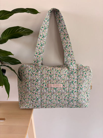 Sac polochon vert à motif floral, matelassé, avec anses larges et poche avant. Sac de voyage féminin élégant.