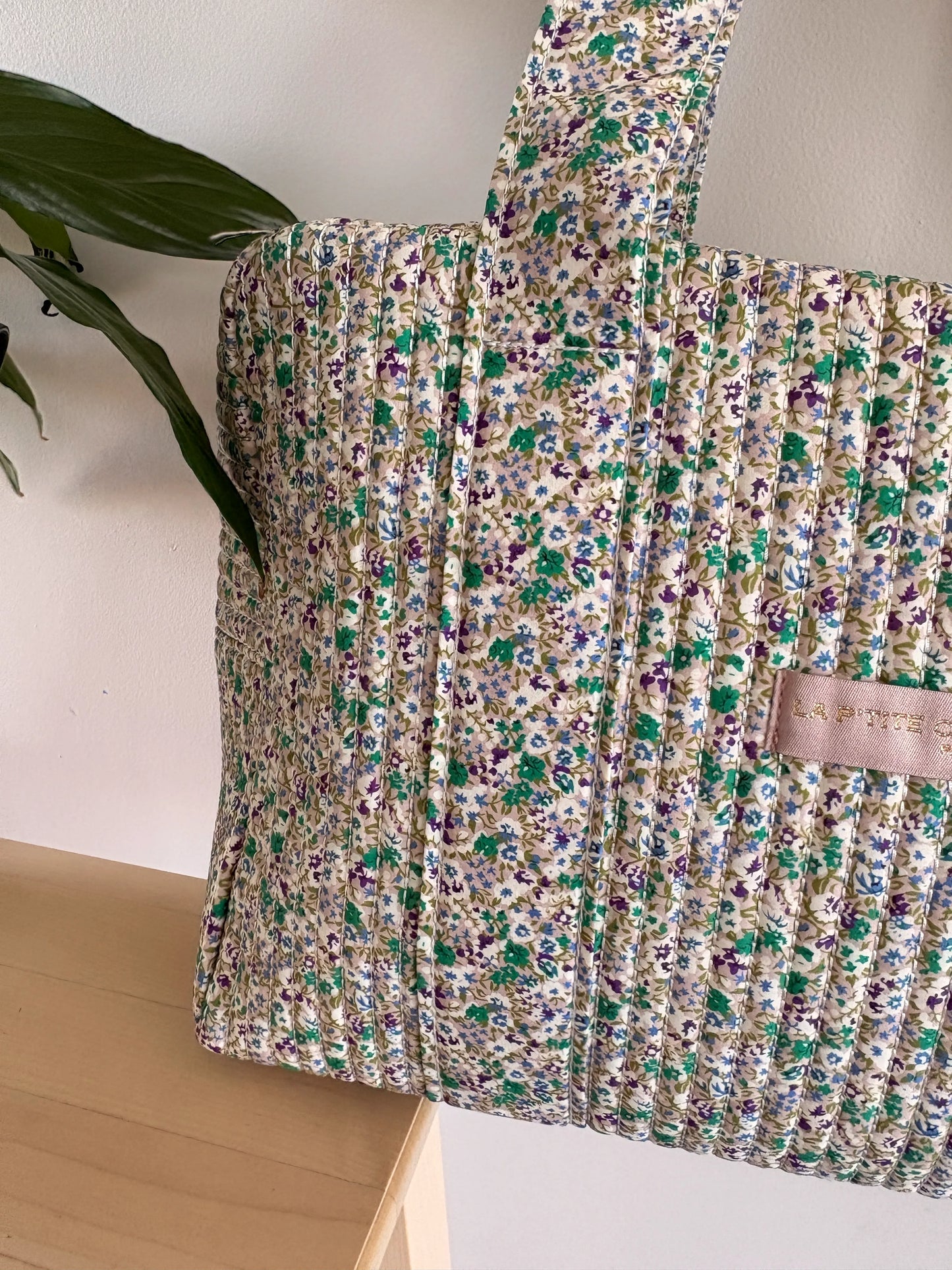 Sac polochon vert à motif floral, voyage femme, texture matelassée épaisse et détails couture.
