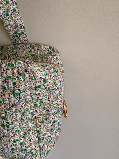 Sac polochon vert avec motif floral, section voyage femme matelassé, fermeture éclair dorée visible.