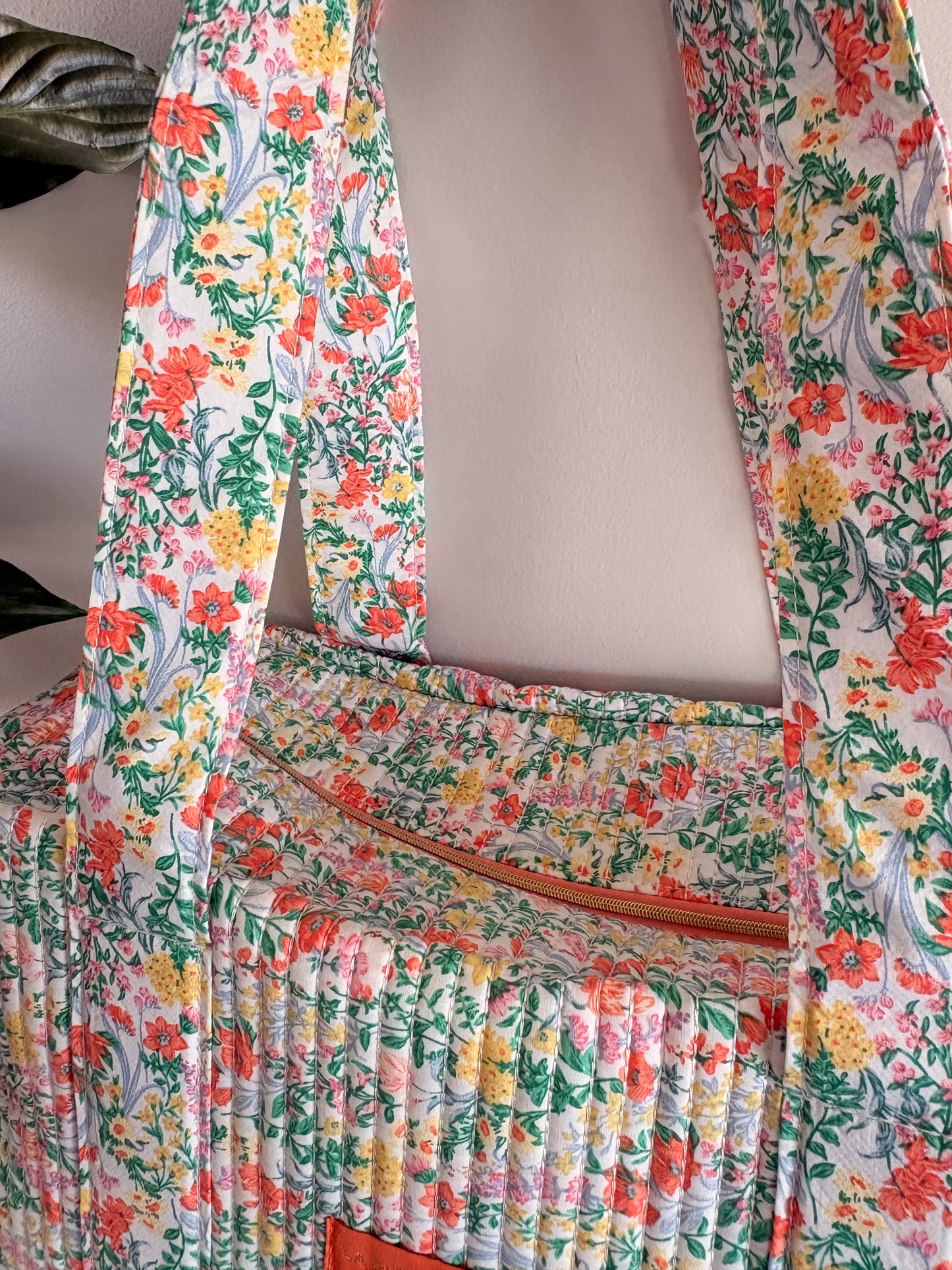 Sac polochon matelassé floral vert menthe avec imprimé fleurs féminines, fermeture zippée visible et ruban plissé sur le tissu.