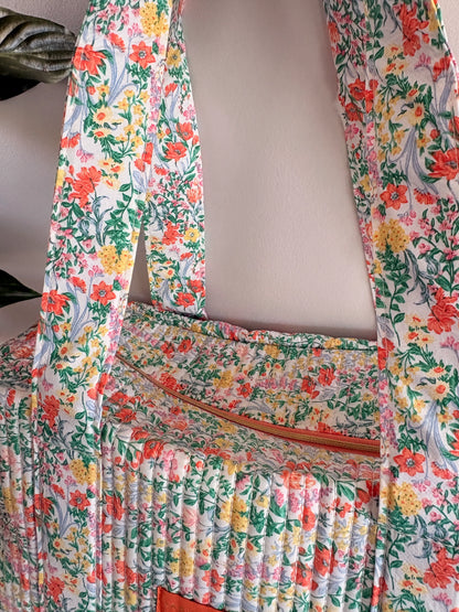 Sac polochon matelassé floral vert menthe avec imprimé fleurs féminines, fermeture zippée visible et ruban plissé sur le tissu.