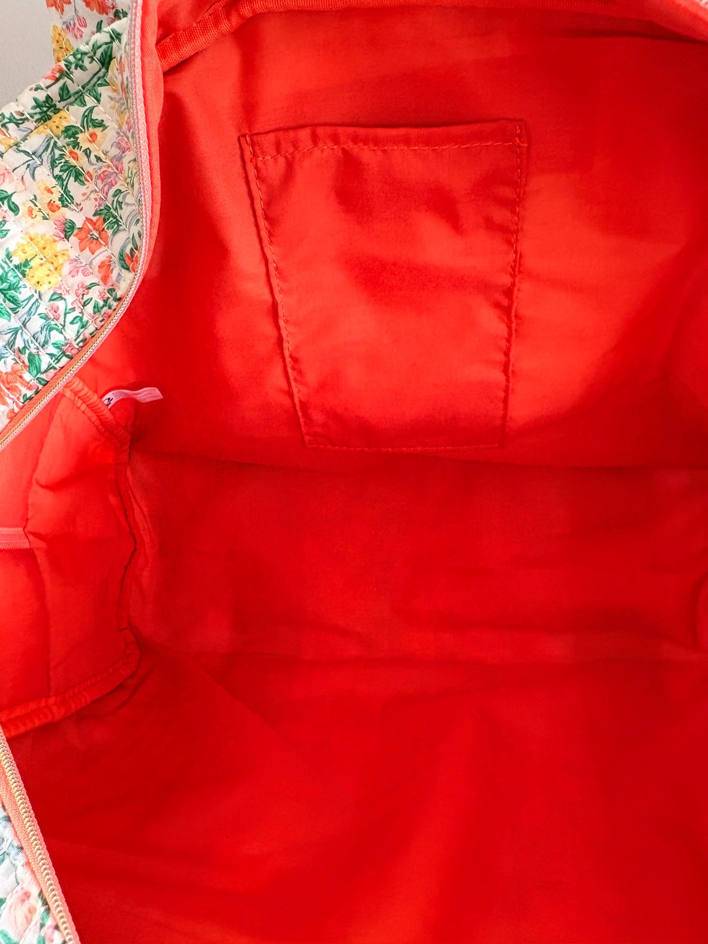 Sac polochon matelassé vert menthe à imprimé fleurs femme, intérieur rouge vif avec pochette plaquée et zippée.