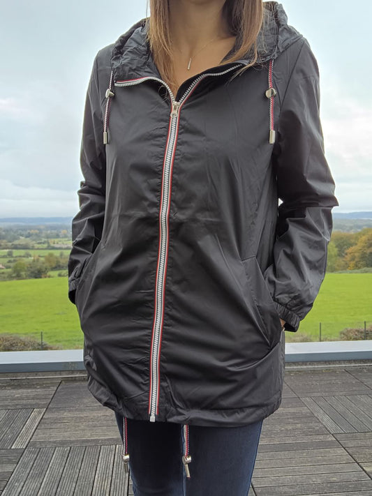 Woman wearing Laura Jo black raincoat with hood, standing outdoors on terrace, Le Petit Placard